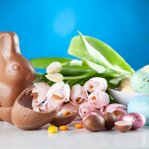 A vibrant Easter display featuring a chocolate bunny, pastel eggs, and tulips.